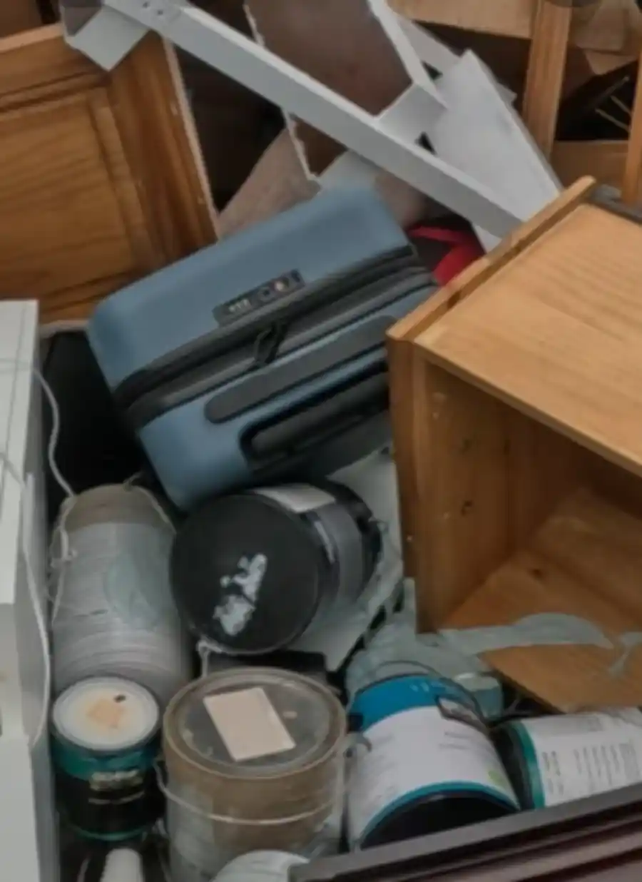 Storage unit packed with boxes, luggage, and furniture before a cleanout in Hemet, CA
